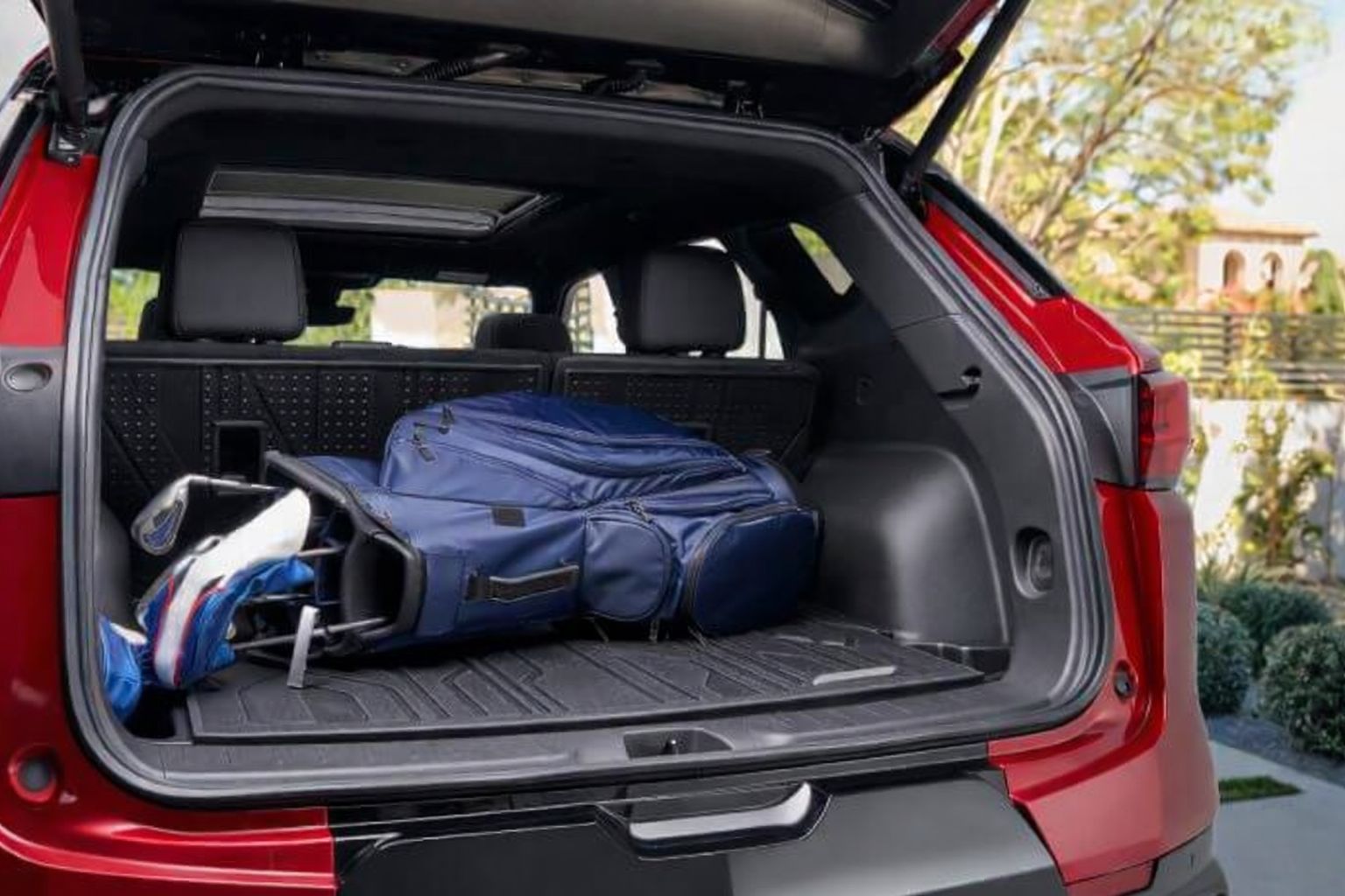 En blå golfbag placerad i bagageutrymmet på en röd bil.