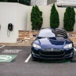 En mörkblå Tesla parkerad på en laddplats för elbilar.