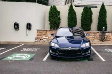 En mörkblå Tesla parkerad på en laddplats för elbilar.