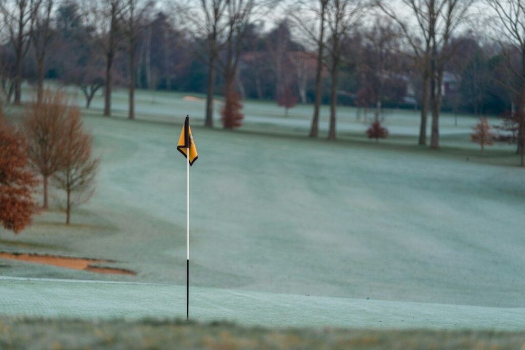 Frosttäckt golfbana med gulsvart flagga på greenen