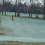 Frosttäckt golfbana med gulsvart flagga på greenen