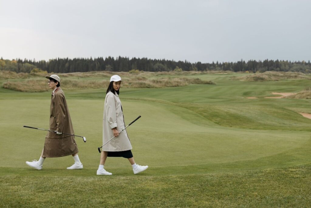 Två golfare går över fairway med klubborna i handen
