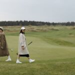 Två golfare går över fairway med klubborna i handen