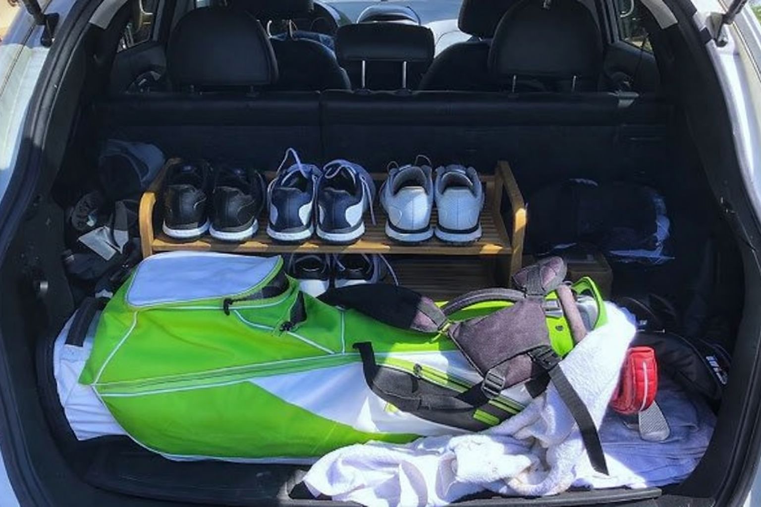 Golfbag och skoställ med golfskor i bakluckan på en bil.